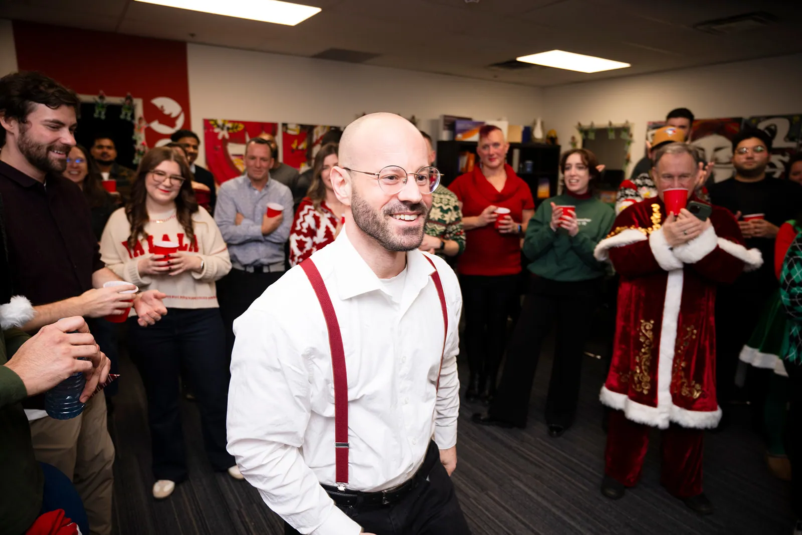 A colleague grinning in the middle of a circle of clapping teammates